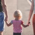 両親と手をつないでいる子供の写真